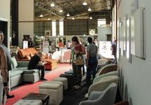 Visitantes circulando entre estandes de sofás em evento da CNP Eventos