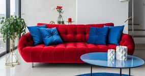 Poltrona vermelha em destaque com iluminação artística em tons de azul e vermelho.